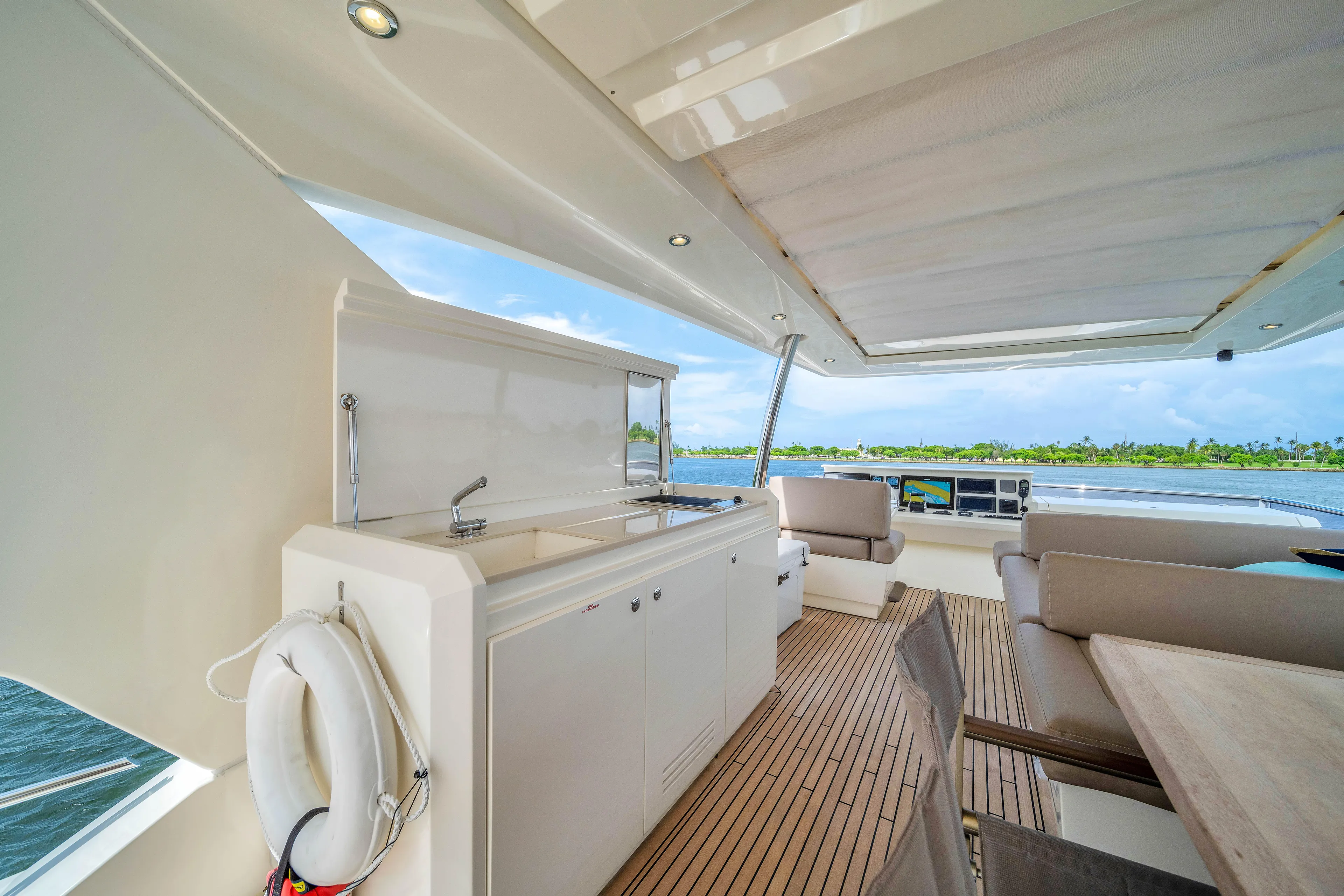 Oceana Yacht Photos Pics Luxurious 2015 Prestige 750 yacht deck with seating and kitchenette, overlooking serene waters.