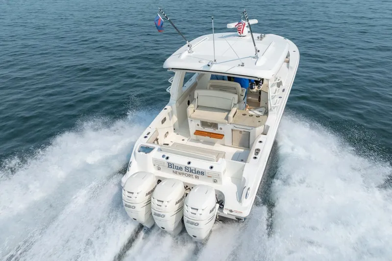 Blue Skies Yacht Photos Pics 2019 Boston Whaler 350 EX REALM cruising on open water, rear view.