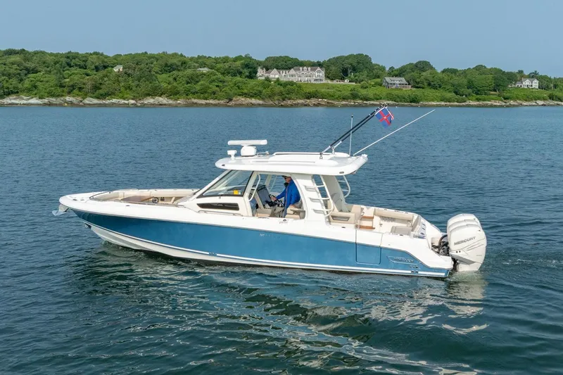 Blue Skies Yacht Photos Pics 2019 Boston Whaler 350 EX REALM cruising on calm waters near a lush shoreline.