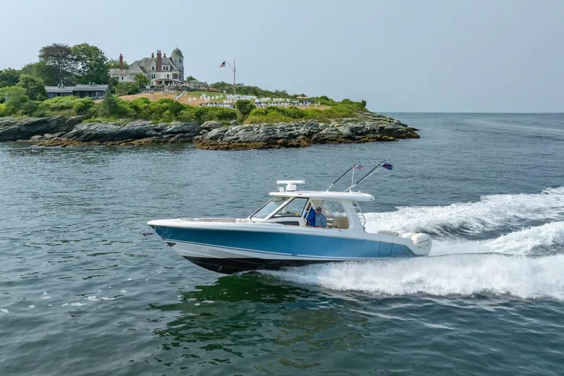 Blue Skies Yacht Photos Pics 2019 Boston Whaler 350 EX REALM cruising near scenic coastal estate.