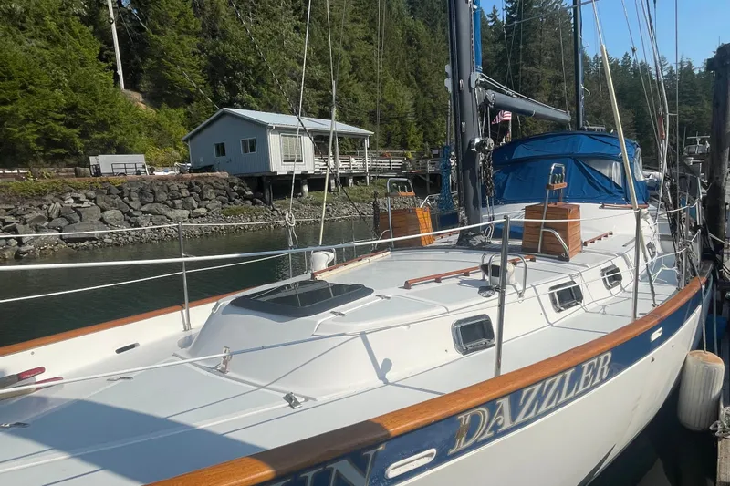 Sun Dazzler Yacht Photos Pics 1981 Mariner 48 sailboat docked near a rustic cabin and lush forest.