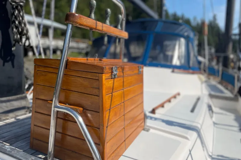 Sun Dazzler Yacht Photos Pics Wooden box on 1981 Mariner 48 yacht deck, with metal railing and blurred background.
