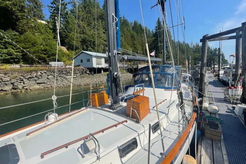 Sun Dazzler Yacht Photos Pics 1981 Mariner 48 sailboat docked in a scenic marina with lush greenery.