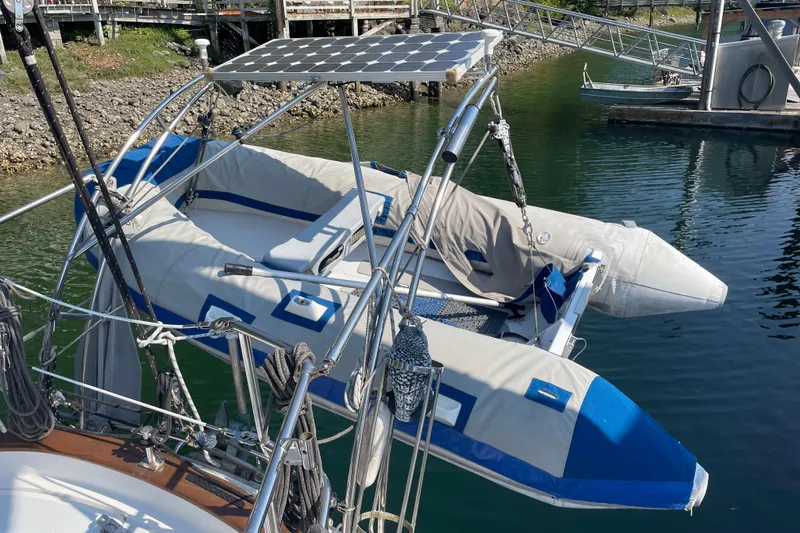 Sun Dazzler Yacht Photos Pics Inflatable boat on 1981 Mariner 48 yacht with solar panel, docked in marina.