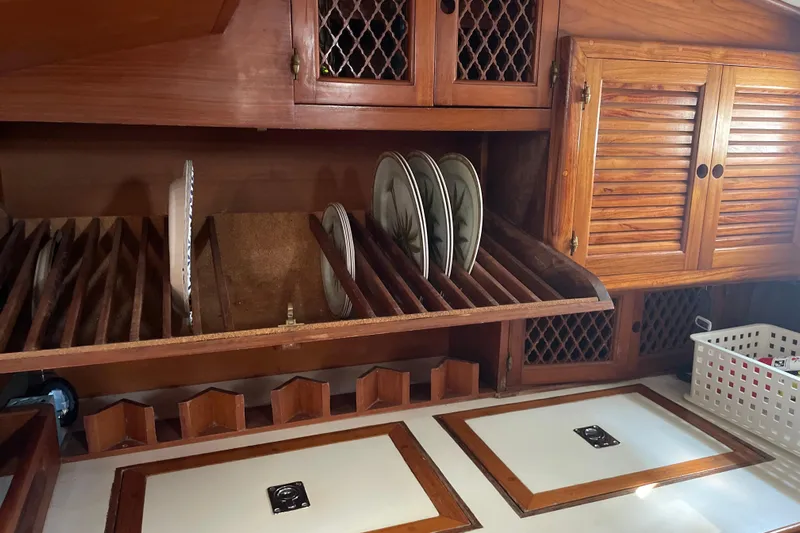 Sun Dazzler Yacht Photos Pics Wooden kitchen storage with plate rack in 1981 Mariner 48 boat interior.
