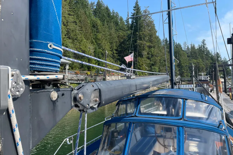 Sun Dazzler Yacht Photos Pics 1981 Mariner 48 sailboat docked, featuring blue canvas and rigging, with forested background.