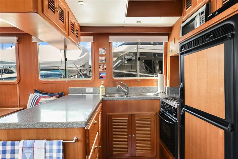 Rogue Yacht Photos Pics 2007 North Pacific NP42 Pilothouse kitchen with wood cabinetry, modern appliances, and large windows.