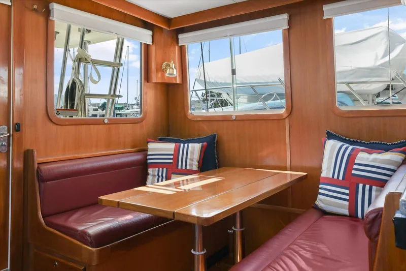 Rogue Yacht Photos Pics Cozy dining area in 2007 North Pacific NP42 Pilothouse with wood finish and nautical-themed cushions.
