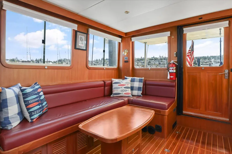 Rogue Yacht Photos Pics Interior of 2007 North Pacific NP42 Pilothouse with red seating and nautical-themed pillows.