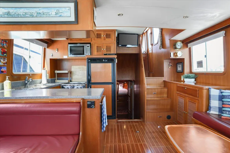 Rogue Yacht Photos Pics Interior of 2007 North Pacific NP42 Pilothouse with kitchen, dining area, and wooden finishes.