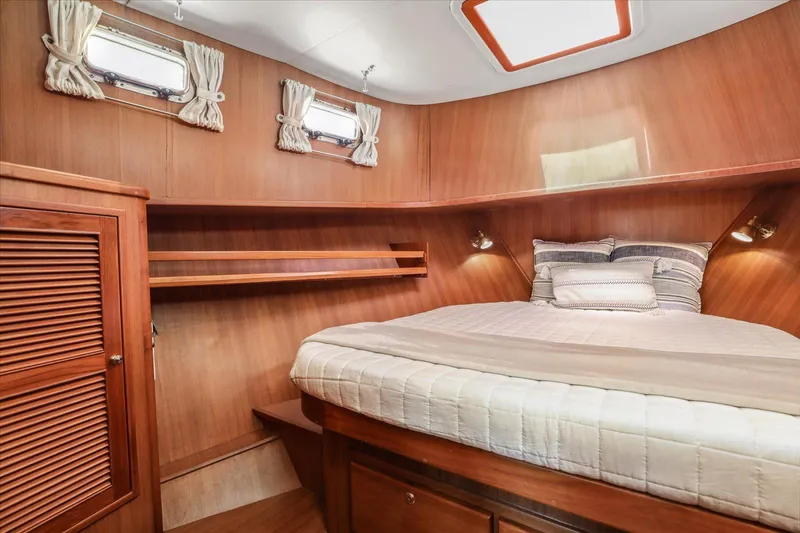 Rogue Yacht Photos Pics Cozy cabin interior of 2007 North Pacific NP42 Pilothouse with wood paneling and comfortable bedding.