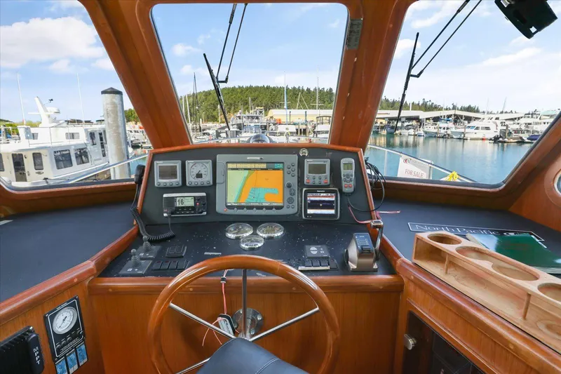 Rogue Yacht Photos Pics Pilothouse interior of 2007 North Pacific NP42, featuring navigation equipment and marina view.