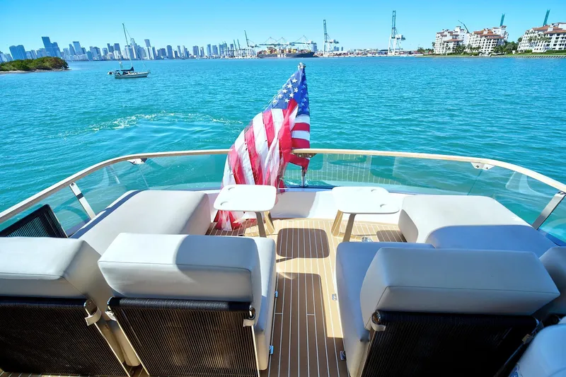 Raw Wave Yacht Photos Pics Luxury Fairline Squadron 68 yacht deck with American flag, overlooking city skyline and ocean.