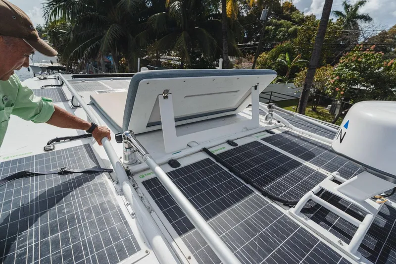  Yacht Photos Pics 2024 YachtCat 41 with solar panels and open hatch, surrounded by tropical trees.
