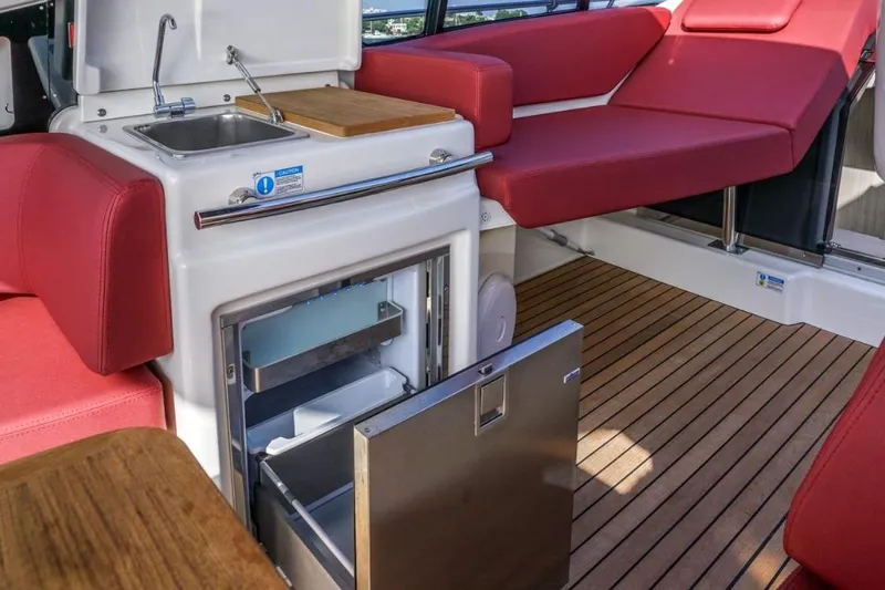  Yacht Photos Pics 2022 Cranchi M44HT yacht interior with kitchenette, red seating, and wooden flooring.