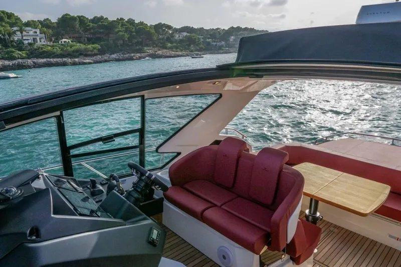  Yacht Photos Pics 2022 Cranchi M44HT yacht interior with red seating and wooden table, overlooking serene waters.