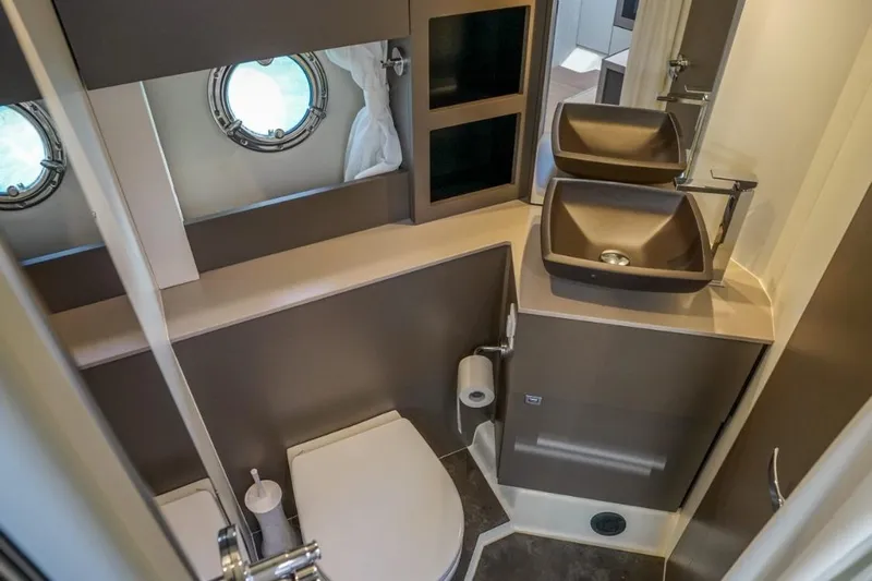 Yacht Photos Pics Luxurious bathroom in 2022 Cranchi M44HT yacht with modern fixtures and porthole window.
