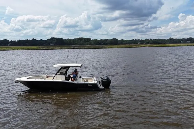  Yacht Photos Pics 2026 Scout 277 LXF boat cruising on a calm river under a cloudy sky.