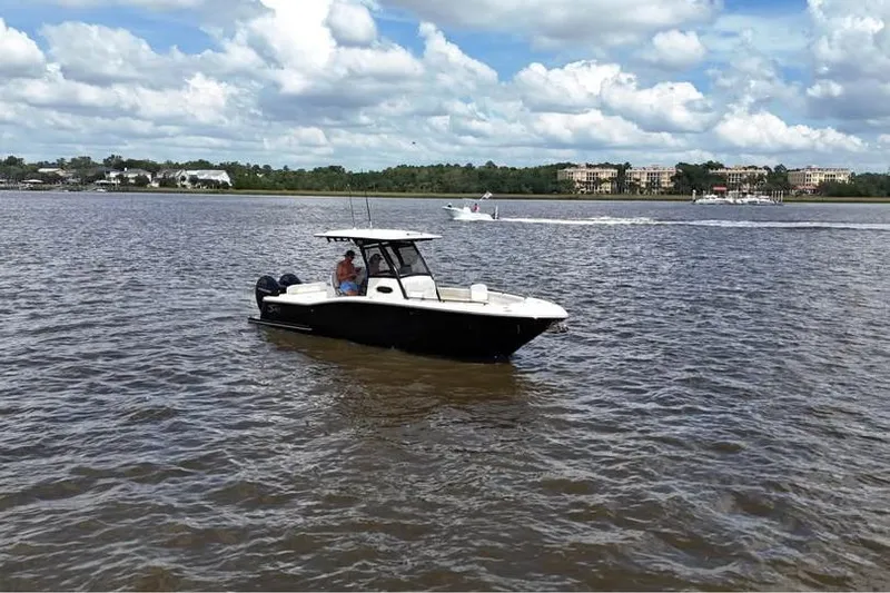  Yacht Photos Pics 2026 Scout 277 LXF boat cruising on a calm river under a partly cloudy sky.