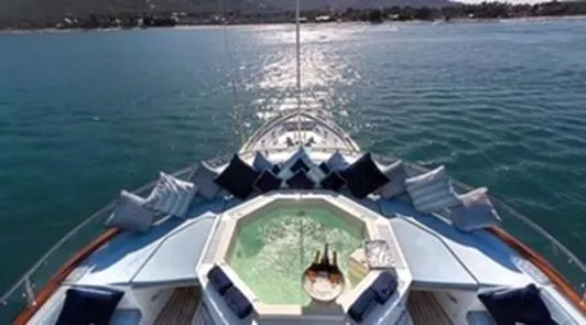 Ligaya Yacht Photos Pics Luxurious yacht deck with jacuzzi, surrounded by cushions, on calm ocean waters.