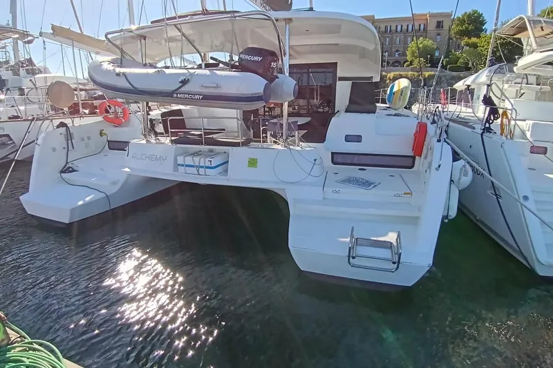  Yacht Photos Pics 2019 Lagoon 42 catamaran docked, featuring a Mercury dinghy and spacious deck area.