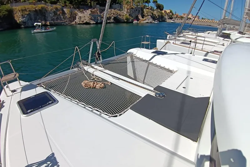  Yacht Photos Pics 2019 Lagoon 42 catamaran on serene water, featuring spacious deck and netting.