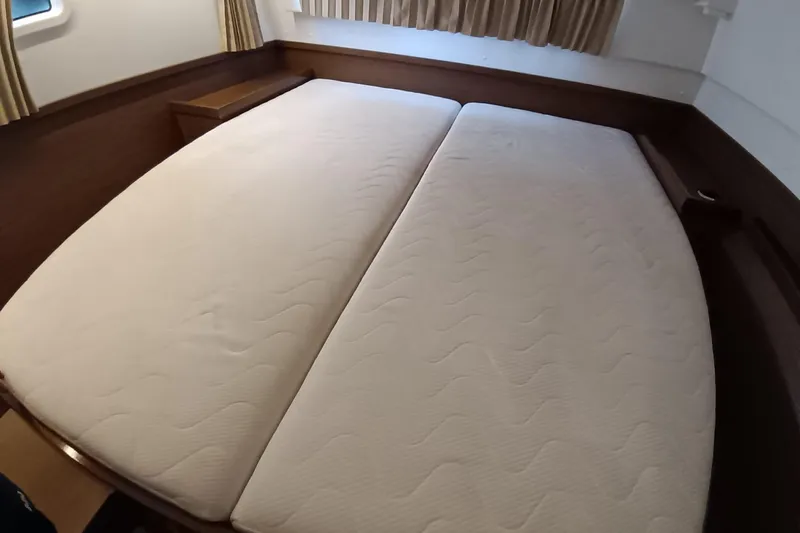  Yacht Photos Pics Interior cabin of 2019 Lagoon 42 catamaran with twin mattresses and wooden accents.