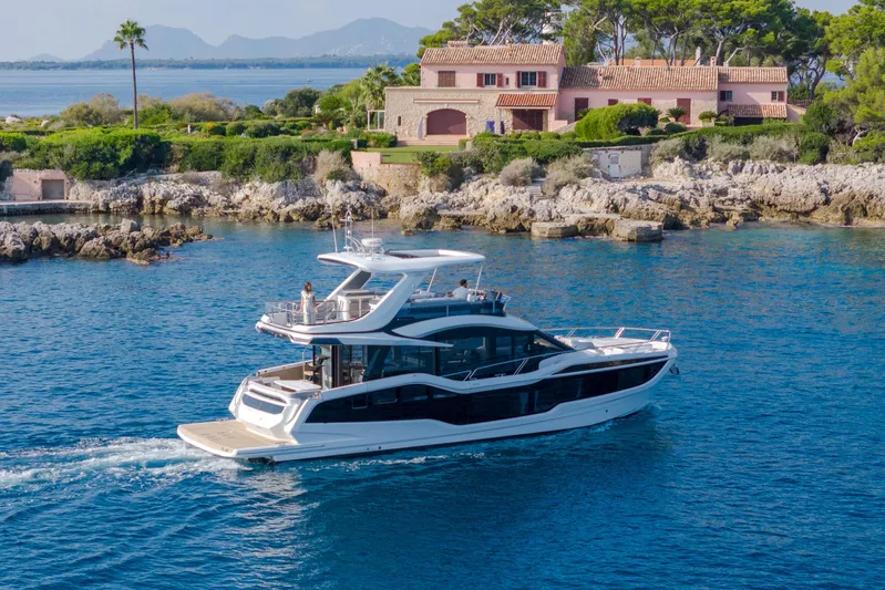  Yacht Photos Pics Luxury 2026 Galeon 560 Fly yacht cruising near a scenic coastal villa.