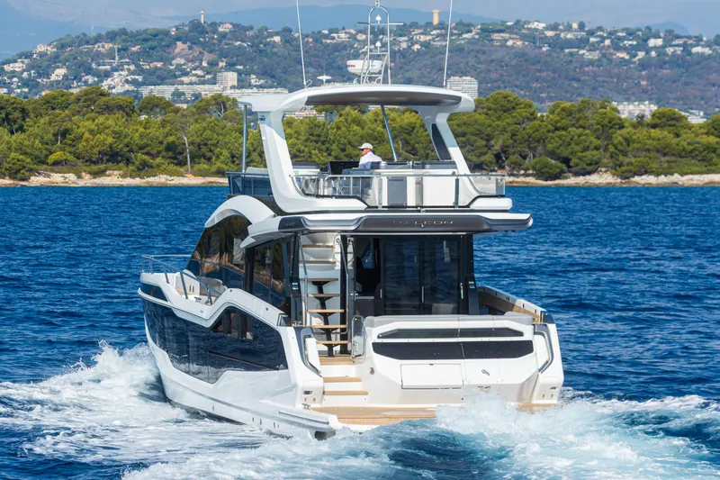  Yacht Photos Pics 2026 Galeon 560 Fly yacht cruising on blue waters near a scenic coastline.