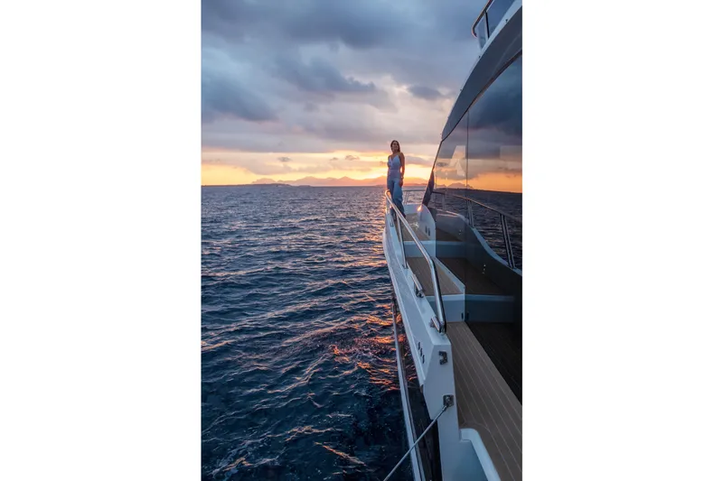  Yacht Photos Pics 2026 Galeon 560 Fly yacht at sunset, woman standing on deck, ocean view.
