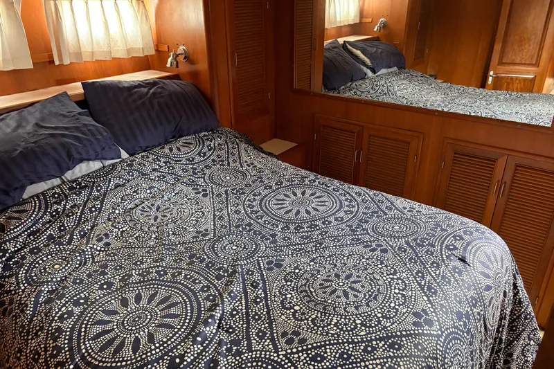 Majestic Z Yacht Photos Pics Cozy bedroom in 1990 Angel Pilothouse with patterned bedding and wooden cabinetry.