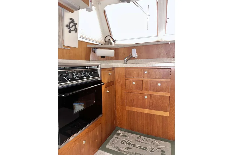 Ohana Yacht Photos Pics 1999 Mainship 390 Trawler kitchen with wooden cabinets, stove, and sink.