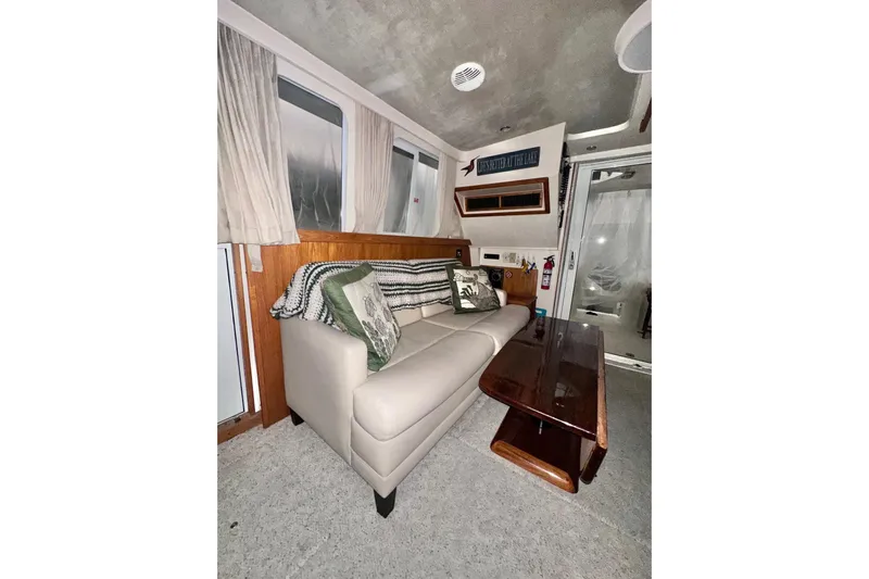 Ohana Yacht Photos Pics Interior of 1999 Mainship 390 Trawler with beige sofa, wooden table, and decorative pillows.