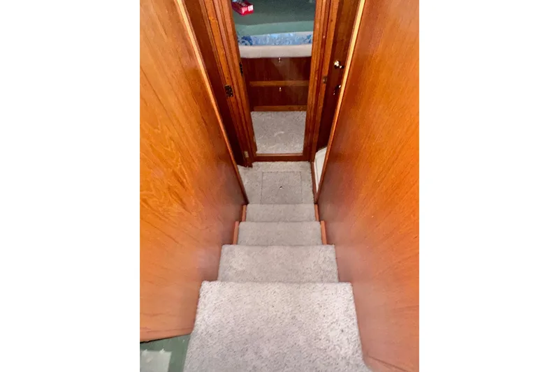 Ohana Yacht Photos Pics Staircase inside 1999 Mainship 390 Trawler with wooden walls and carpeted steps.