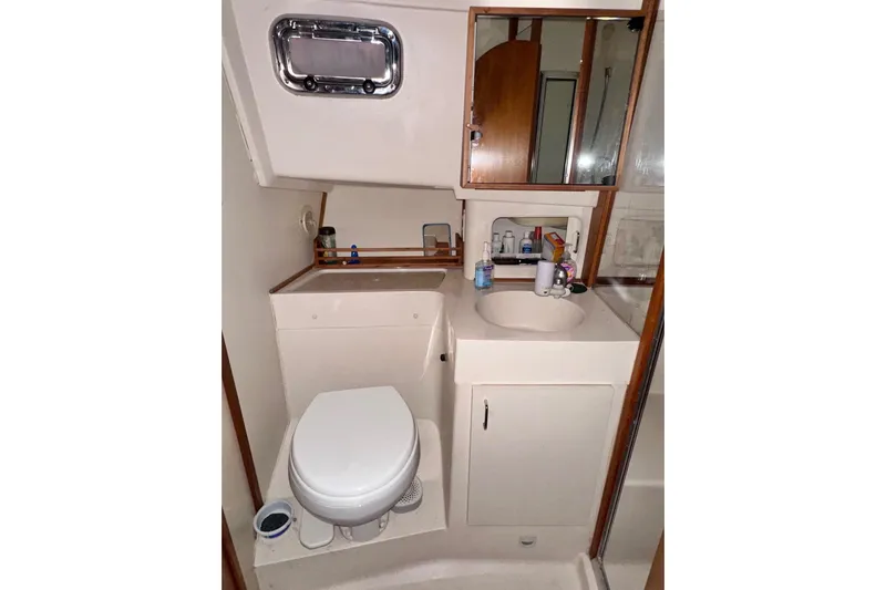Ohana Yacht Photos Pics Bathroom interior of 1999 Mainship 390 Trawler with sink, toilet, and mirror.