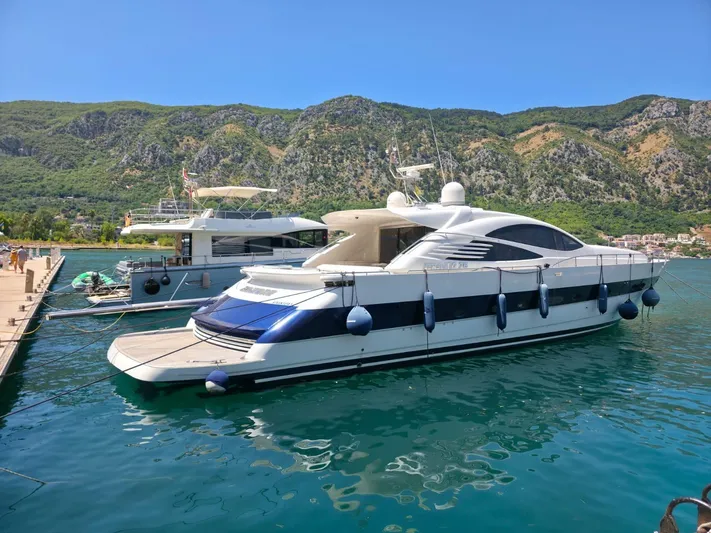 Evazione Yacht Photos Pics Luxury 2005 Pershing 67 yacht docked in scenic marina with mountainous backdrop.