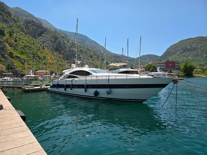Evazione Yacht Photos Pics 2005 Pershing 67 yacht docked in scenic marina with mountainous backdrop.