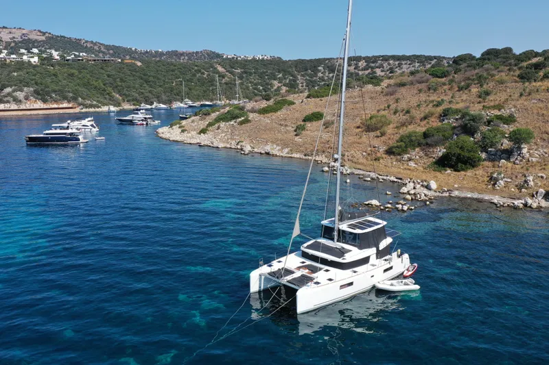 Chicago Yacht Photos Pics Lagoon 52 F catamaran anchored in a scenic bay, surrounded by clear blue water and rocky hills.