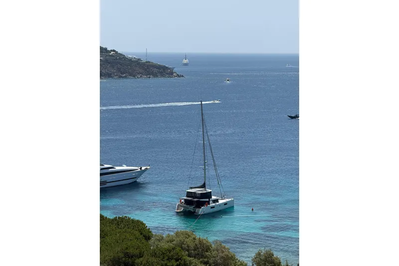 Chicago Yacht Photos Pics 2020 Lagoon 52 F catamaran anchored in clear blue waters near a scenic coastline.