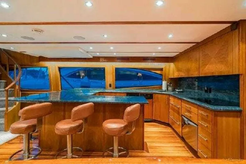 Desperado Yacht Photos Pics Luxurious kitchen area in 2008 Hatteras 77 Enclosed Bridge yacht with bar stools and wooden cabinetry.