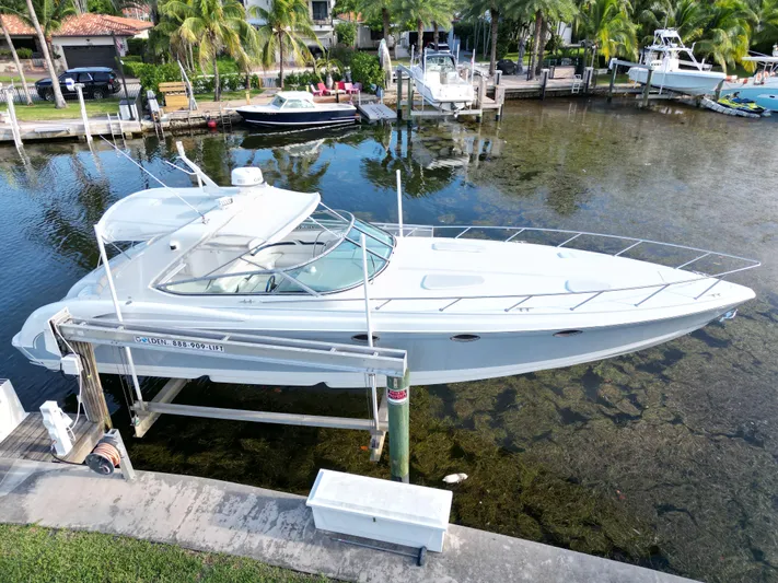 Tony Montana Yacht Photos Pics 1999 Formula 400 Super Sport boat docked near palm trees and waterfront homes.