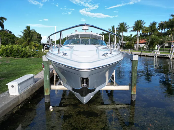 Tony Montana Yacht Photos Pics 1999 Formula 400 Super Sport boat docked on a lift, surrounded by palm trees and clear skies.