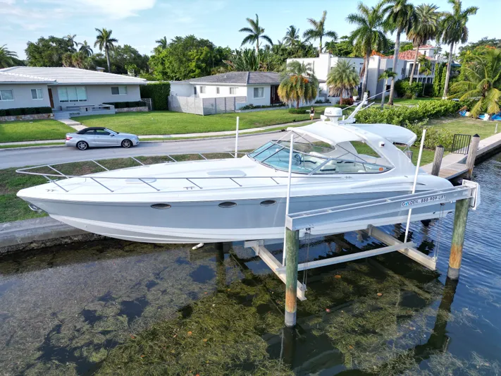 Tony Montana Yacht Photos Pics 1999 Formula 400 Super Sport boat on lift near waterfront homes and palm trees.