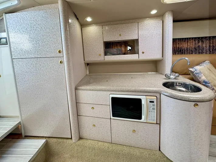 Tony Montana Yacht Photos Pics 1999 Formula 400 Super Sport yacht interior with kitchenette, featuring cabinets, microwave, and sink.