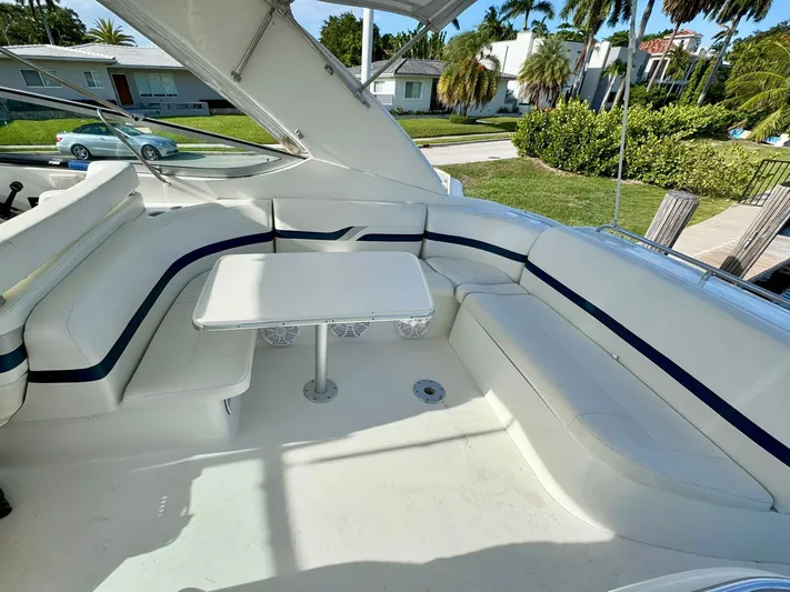 Tony Montana Yacht Photos Pics 1999 Formula 400 Super Sport boat interior with white seating and table, docked near lush greenery.