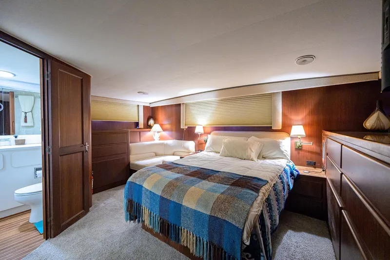 Phantom Yacht Photos Pics Luxurious bedroom interior of 1987 Hatteras 63 Motor Yacht with cozy bed and elegant decor.