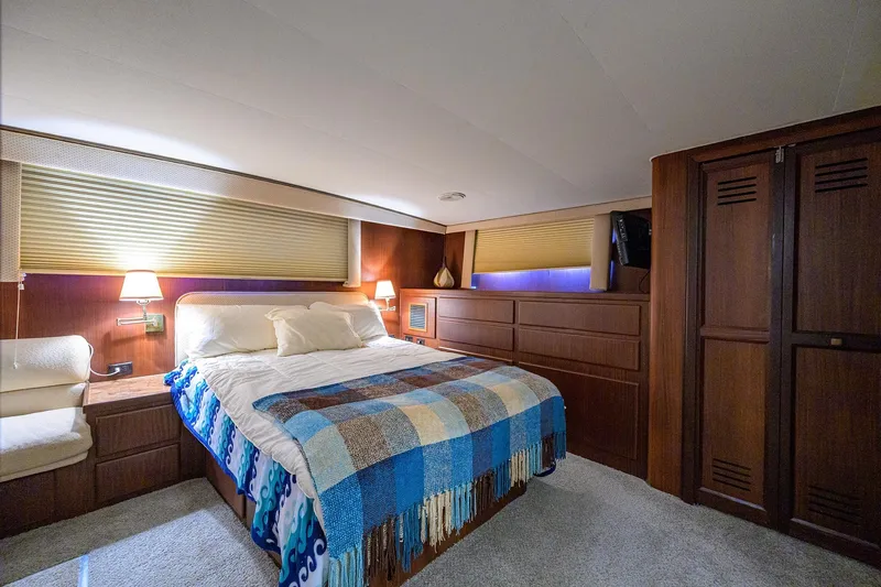 Phantom Yacht Photos Pics Luxurious bedroom interior of 1987 Hatteras 63 Motor Yacht with cozy bed and warm lighting.
