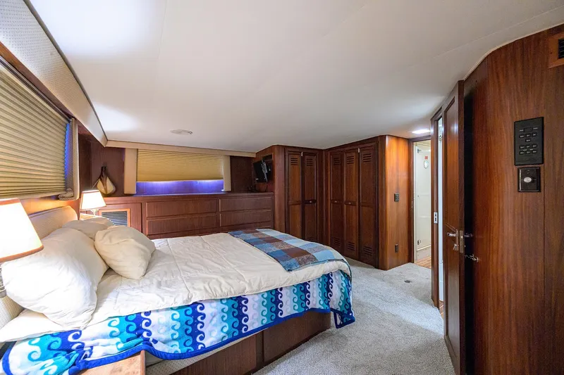 Phantom Yacht Photos Pics Luxurious bedroom interior of 1987 Hatteras 63 Motor Yacht with wood paneling and cozy bedding.