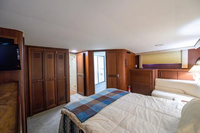 Phantom Yacht Photos Pics Luxurious interior of 1987 Hatteras 63 Motor Yacht bedroom with wood paneling and cozy decor.