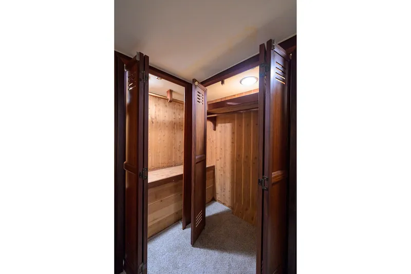 Phantom Yacht Photos Pics Wooden closet interior on 1987 Hatteras 63 Motor Yacht, featuring open doors and carpeted floor.